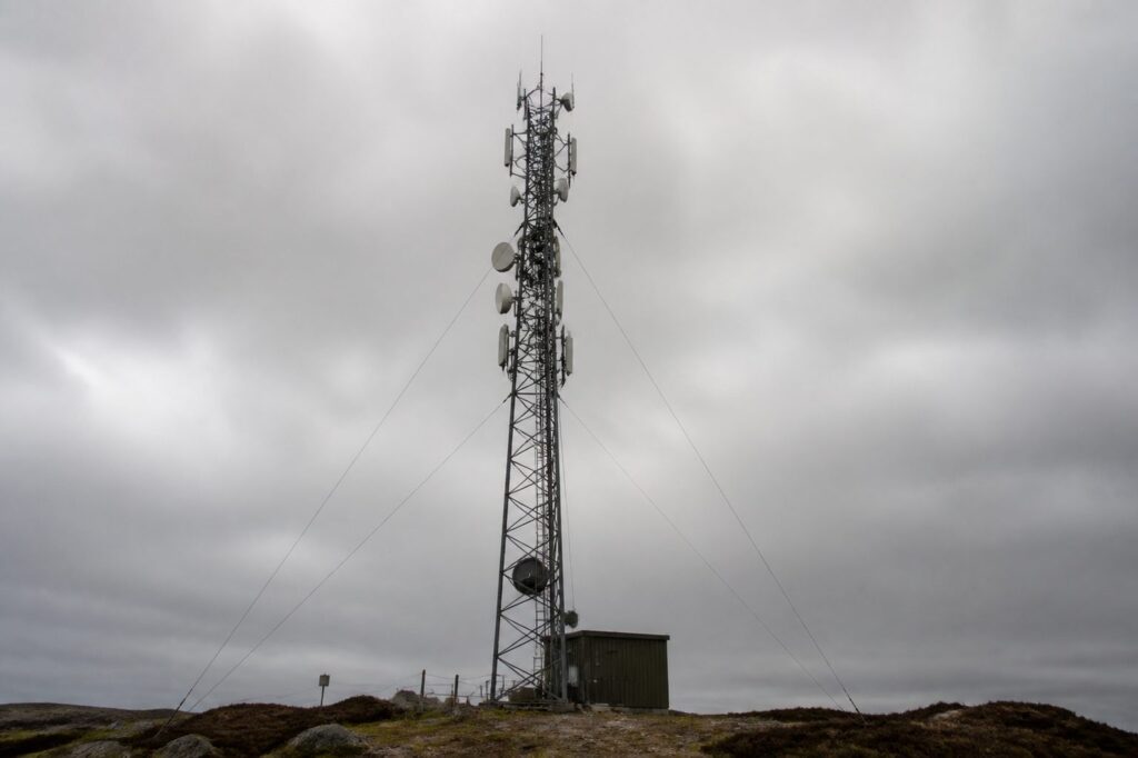 Vakwerkmast met schotelantennes en paneelantennes tegen een grijze lucht